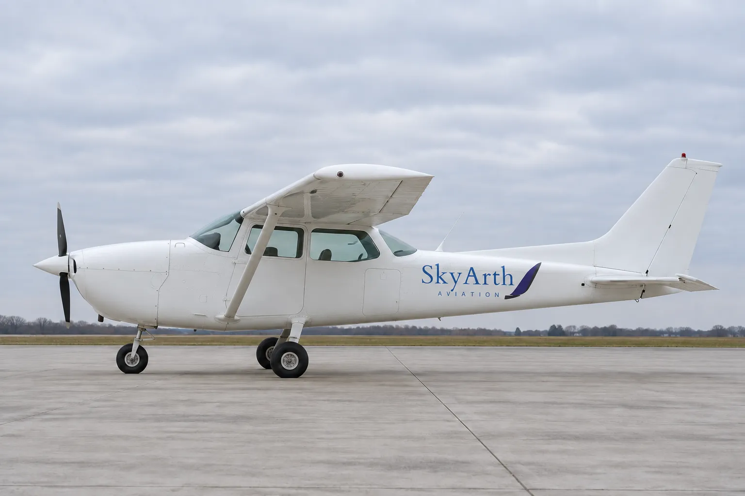 A white single-engine training aircraft in SkyArth Aviation livery, parked on an apron under an overcast sky